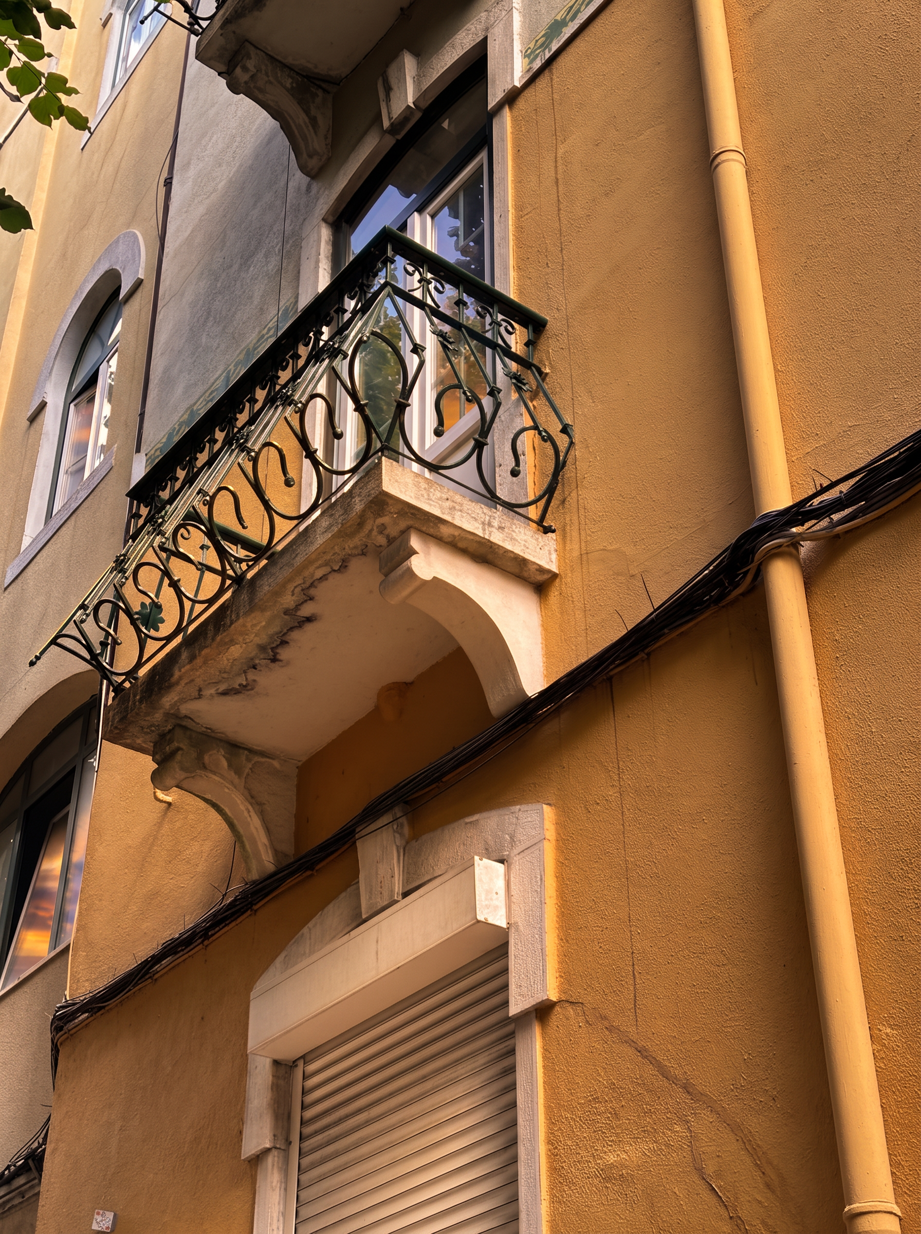 Wrought-iron balcony on the building's ochre facade in sunset light